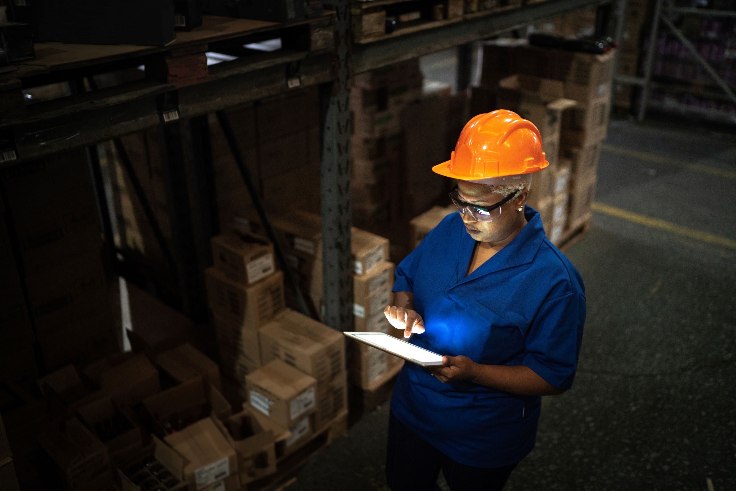 Female worker walking and using digital tablet in warehouse