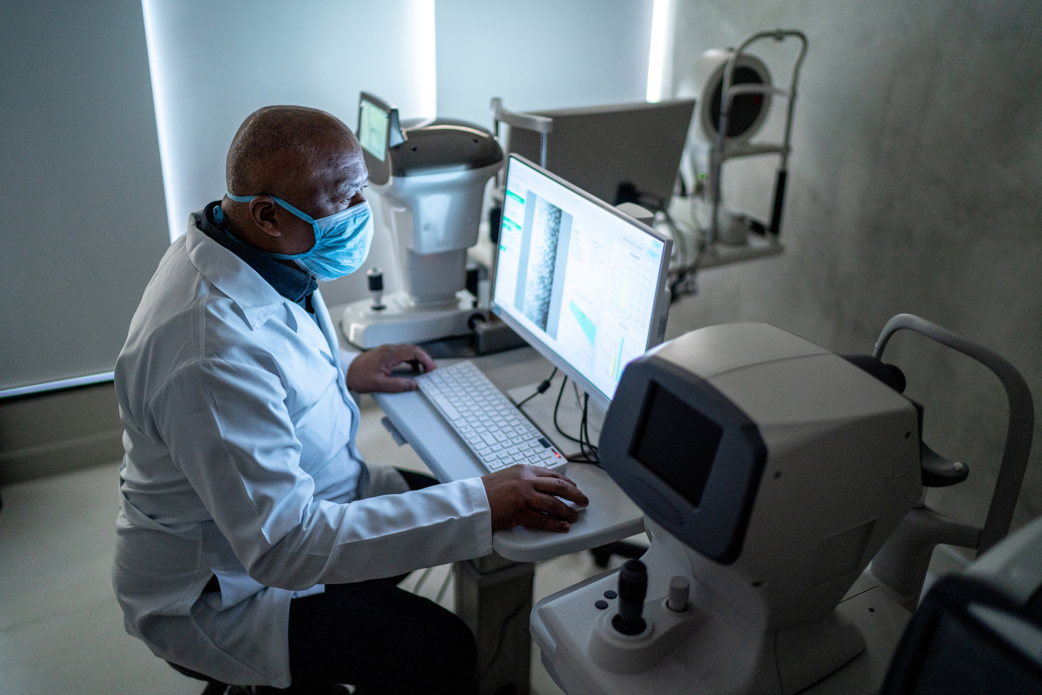 Doctor, wearing a surgical mask, analyzing the exam's results on the monitor
