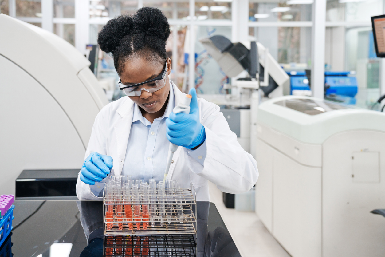 Young female medical worker pipetting chemical in test tube at laboratory