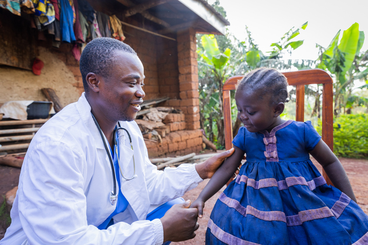 Friendly young doctor visiting a sick baby girl in the village.